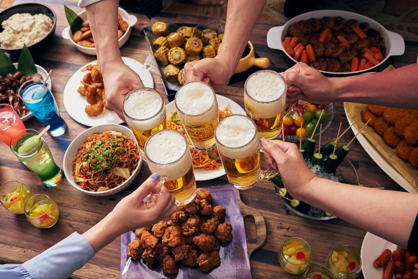 ホテル アゴーラ リージェンシー 大阪堺のビアテラスで、ビールジョッキを持つ複数人の手と料理が並ぶ乾杯イメージ