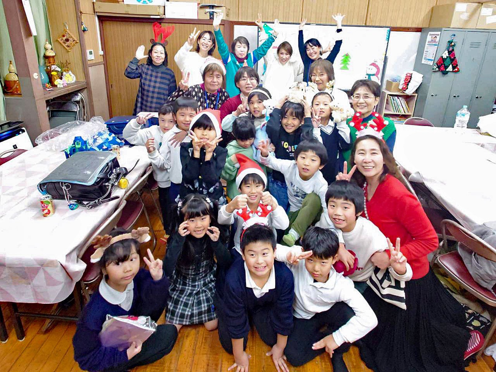 クリスマスの飾り付けがされた室内で、伊藤みどりさんやスタッフ、子どもたちが笑顔で集まる様子