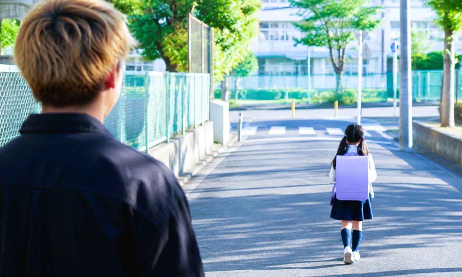 小学生女児の後ろを歩く金髪不審者のイメージ画像