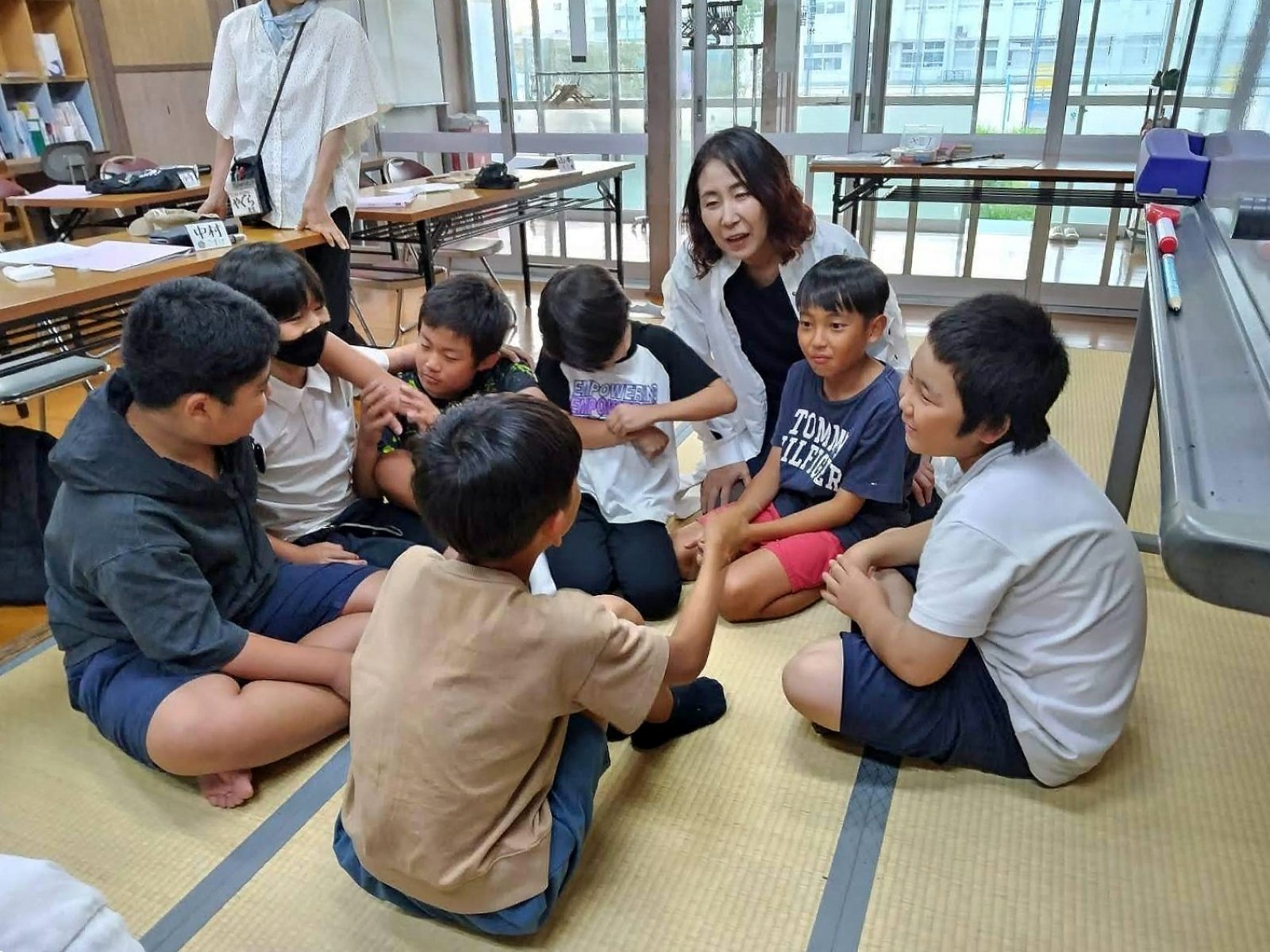 畳の部屋で、伊藤みどりさんを囲んで輪になり交流する子どもたち