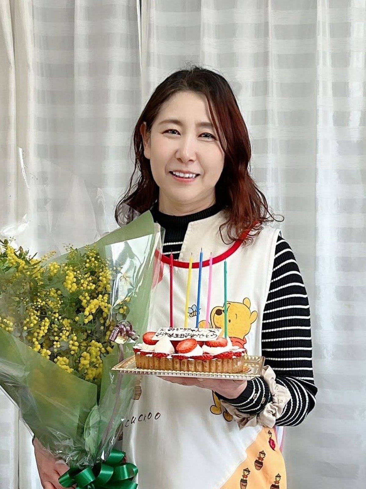 花束と誕生日ケーキを手に笑顔を見せる伊藤みどりさん