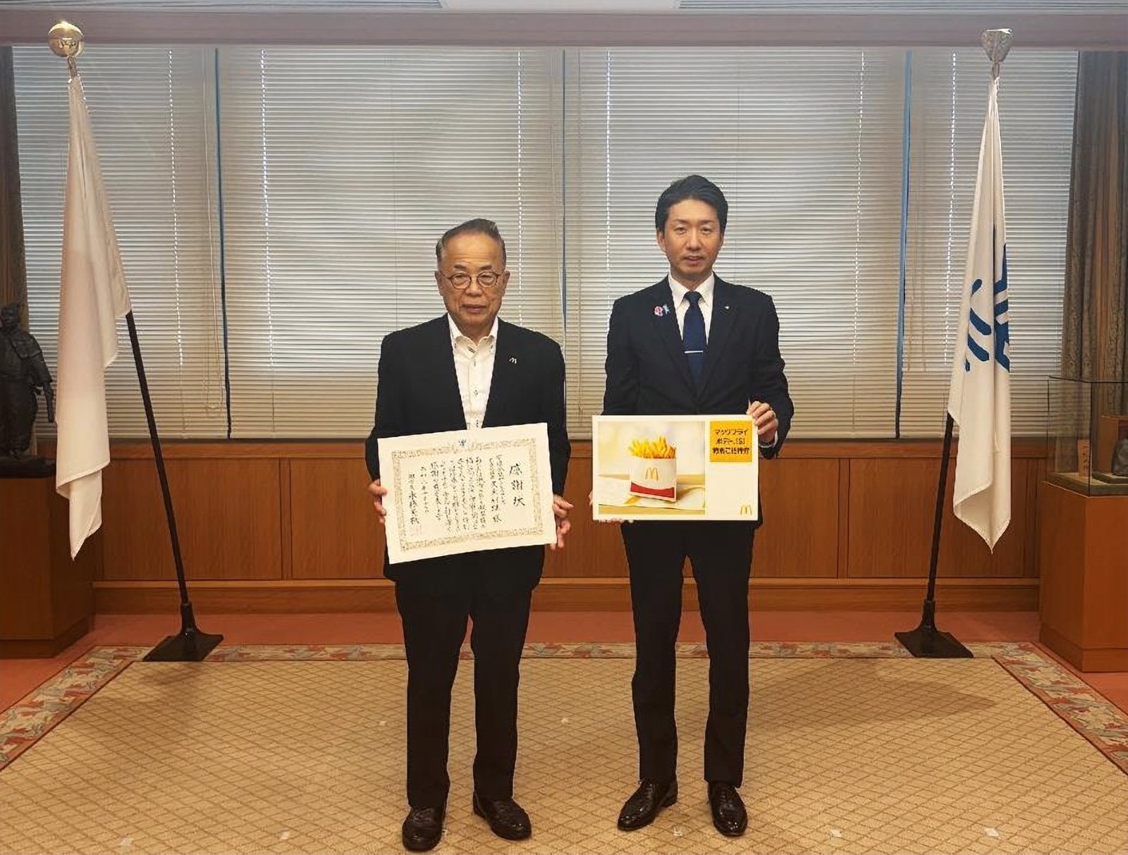 感謝状を持つ有限会社サクセスフーズの久米利雄代表取締役と、マックフライポテトSサイズ特別ご招待券のパネルを持つ永藤英機堺市長