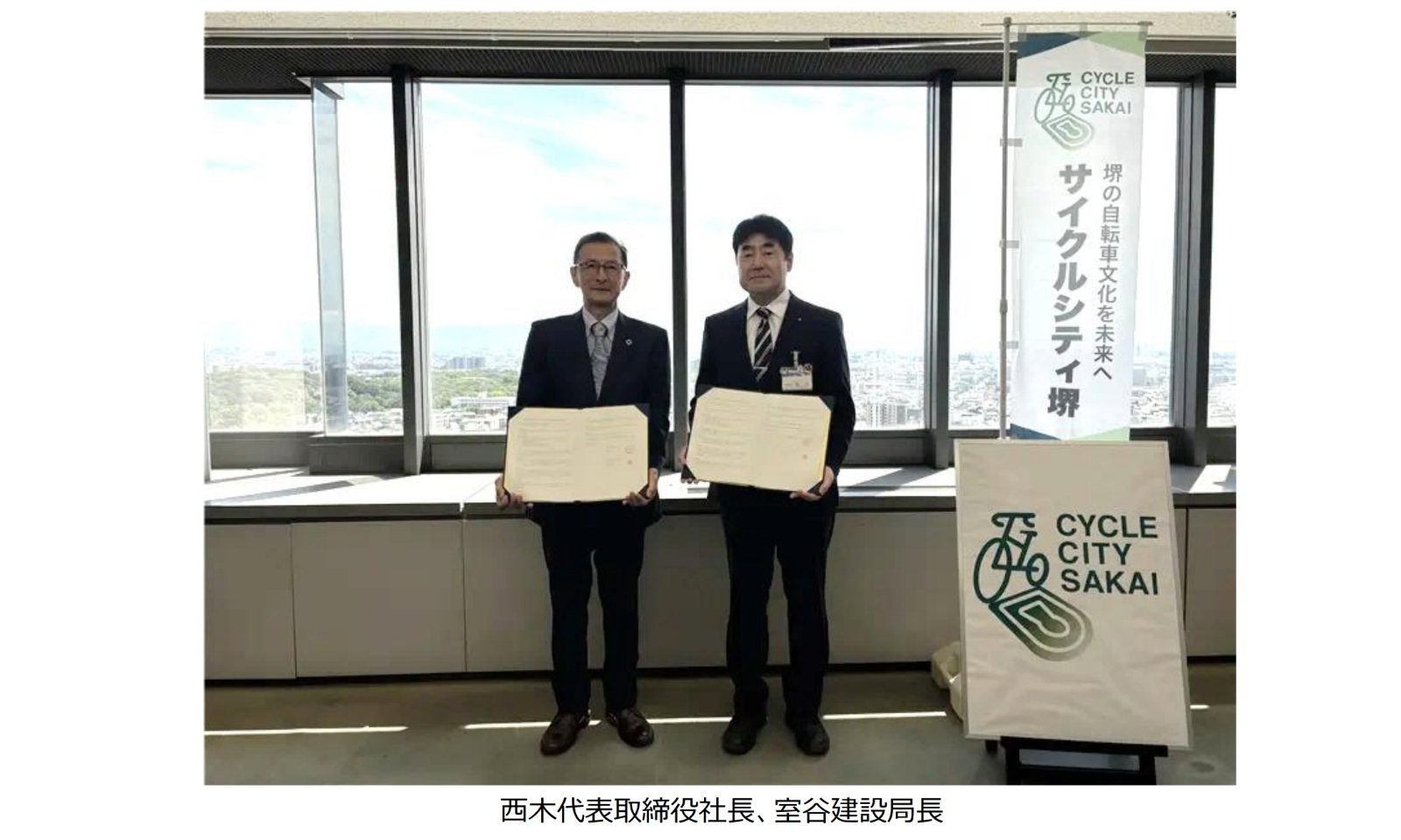 自転車の安全利用と利用促進に関する協定書を手にするアキボウの西木一彦社長と堺市の室谷直樹建設局長