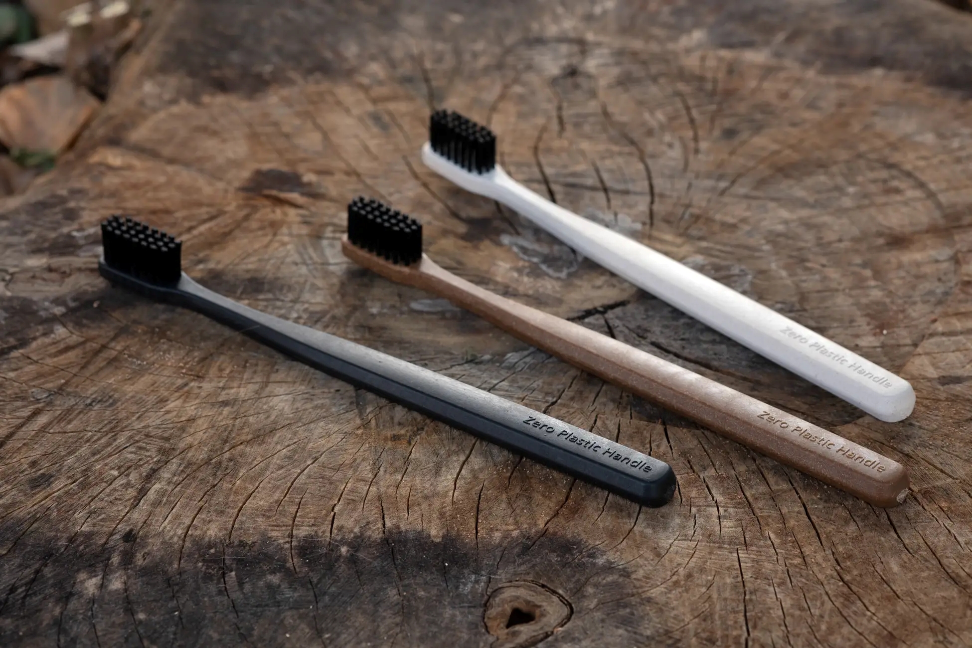 木の切り株の上に並べた「Zero Plastic Handle」の歯ブラシ3色